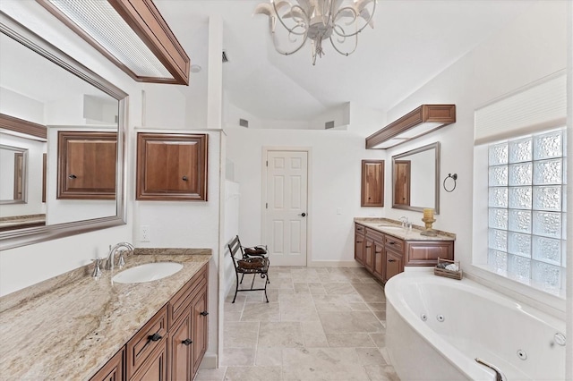 full bath featuring two vanities, a tub with jets, vaulted ceiling, and a sink