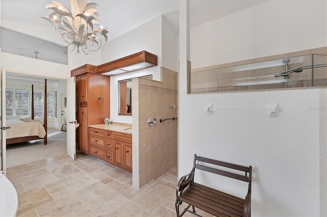 ensuite bathroom featuring connected bathroom, stone finish floor, an inviting chandelier, walk in shower, and vanity