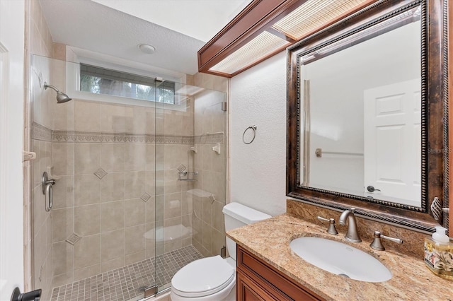 full bath with a textured wall, a shower stall, toilet, and vanity