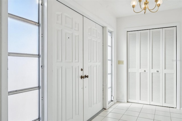 tiled entryway featuring a notable chandelier