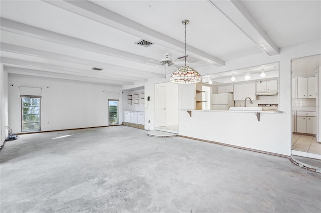 unfurnished living room with a healthy amount of sunlight, sink, and beam ceiling