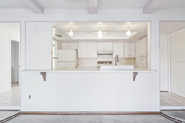 kitchen with beamed ceiling, stove, white fridge, and white cabinets