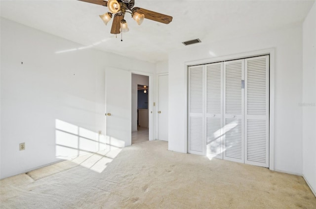 unfurnished bedroom featuring light colored carpet, ceiling fan, and a closet