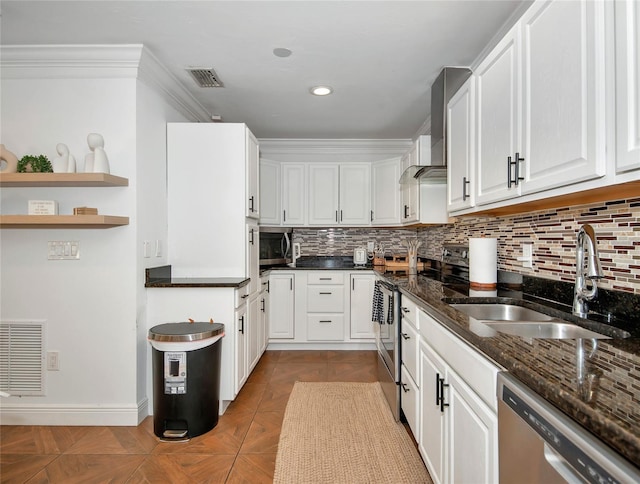 kitchen featuring sink, appliances with stainless steel finishes, white cabinets, dark stone counters, and light parquet floors