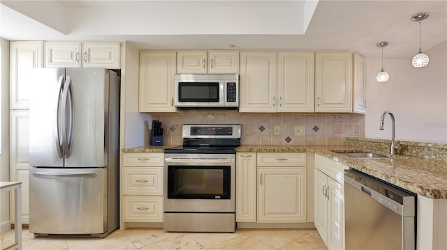 kitchen with stainless steel appliances, a sink, backsplash, and cream cabinets