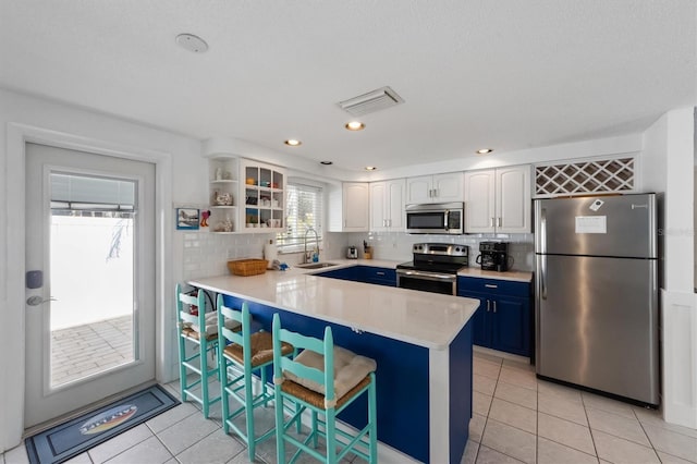 kitchen featuring a kitchen bar, appliances with stainless steel finishes, sink, blue cabinets, and white cabinets