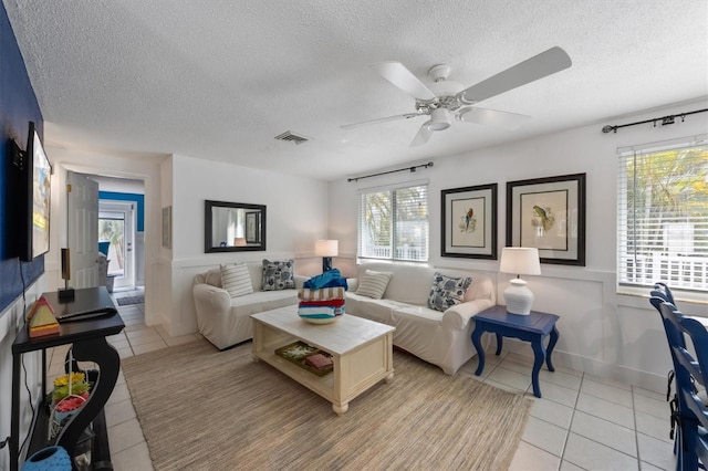 tiled living room with ceiling fan and a textured ceiling