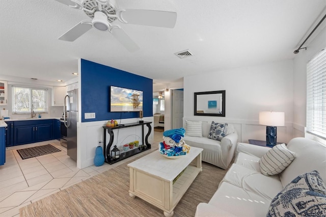 tiled living room featuring ceiling fan and sink