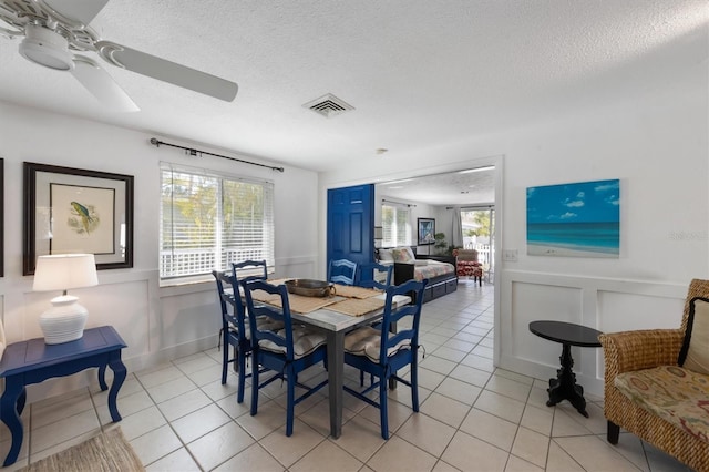 dining space featuring ceiling fan, plenty of natural light, light tile patterned floors, and a textured ceiling