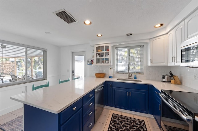 kitchen featuring white cabinetry, stainless steel appliances, blue cabinets, sink, and light tile patterned floors