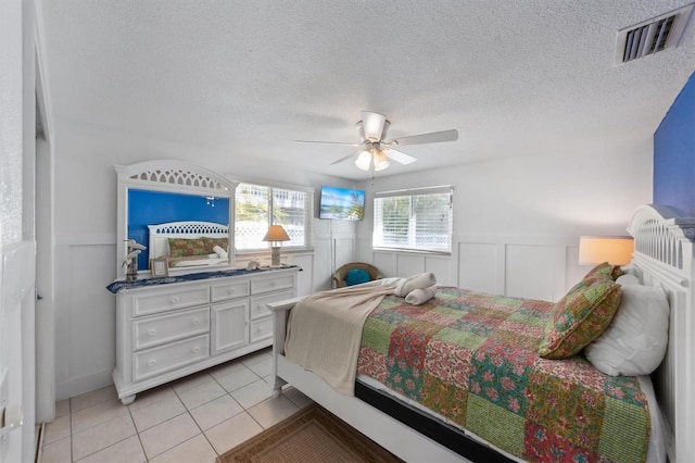 bedroom with a textured ceiling, ceiling fan, and light tile patterned floors