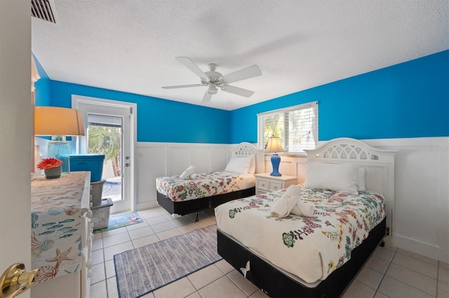 tiled bedroom with ceiling fan, access to outside, and a textured ceiling