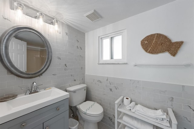 bathroom featuring toilet, tile walls, and vanity