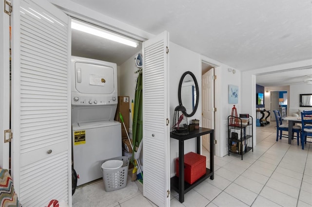 laundry room featuring light tile patterned floors and stacked washer / dryer