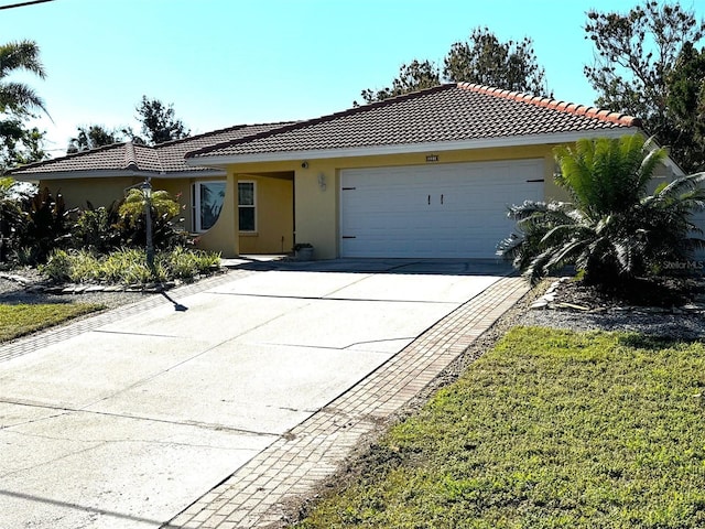 ranch-style home with an attached garage, a tile roof, concrete driveway, and stucco siding