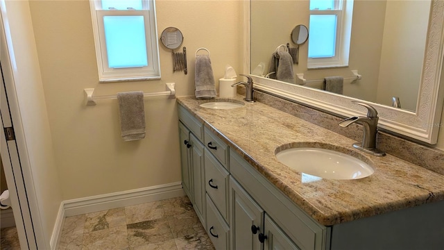 bathroom with a sink, baseboards, and double vanity