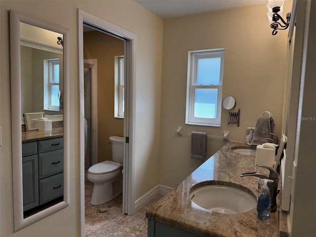 bathroom with a shower with shower door, a sink, baseboards, and double vanity