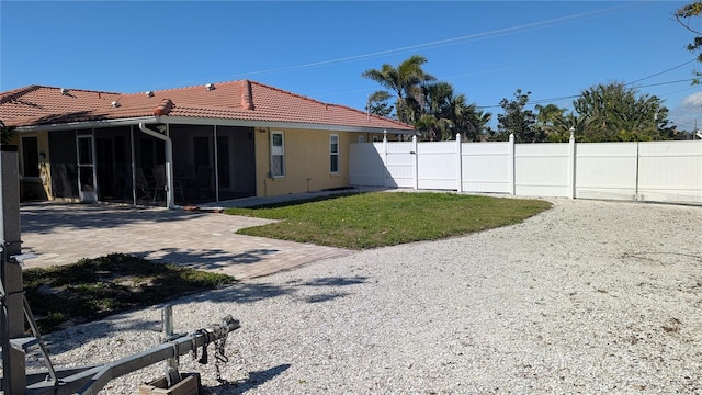 back of property featuring fence, a sunroom, a tiled roof, a yard, and stucco siding