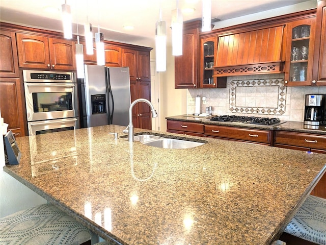 kitchen with tasteful backsplash, dark stone counters, appliances with stainless steel finishes, a kitchen bar, and a sink