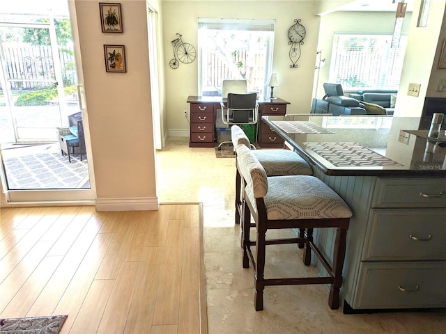 interior space featuring dark countertops, light wood-style floors, baseboards, and a wealth of natural light