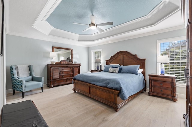 bedroom with a tray ceiling, light hardwood / wood-style flooring, ornamental molding, and a textured ceiling