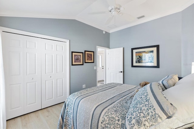 bedroom with crown molding, ceiling fan, vaulted ceiling, a closet, and light wood-type flooring