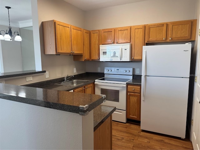 kitchen with sink, white appliances, dark hardwood / wood-style floors, decorative light fixtures, and kitchen peninsula