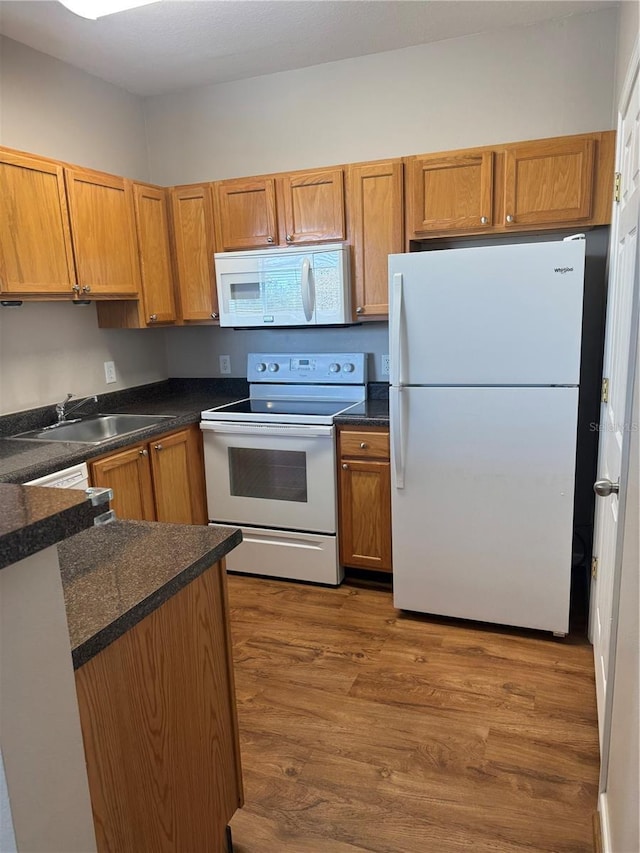 kitchen featuring sink, hardwood / wood-style floors, and white appliances