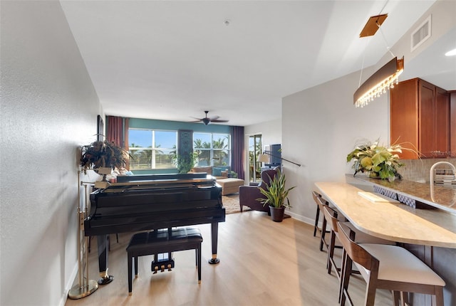 living area featuring light hardwood / wood-style floors, sink, and ceiling fan