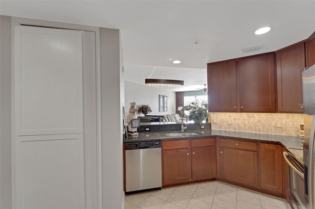 kitchen with range, sink, stainless steel dishwasher, light tile patterned floors, and dark stone countertops