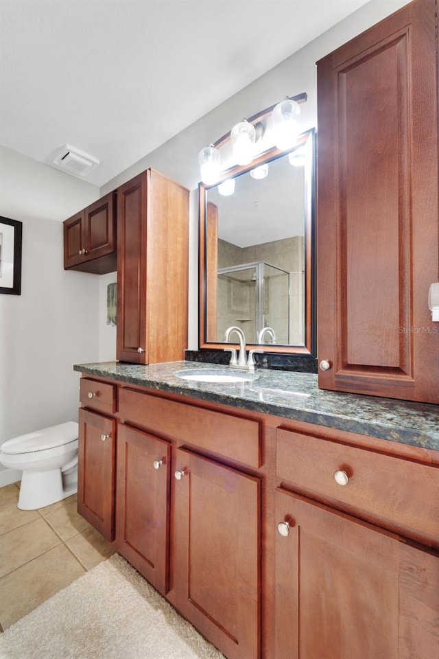 bathroom with tile patterned floors, toilet, vanity, and a shower with door