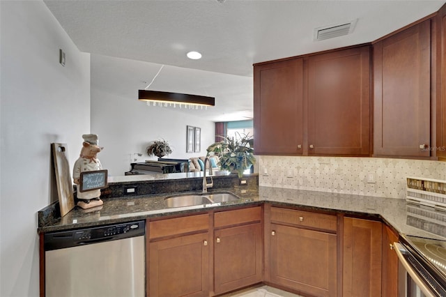 kitchen featuring kitchen peninsula, stainless steel appliances, sink, dark stone countertops, and decorative backsplash