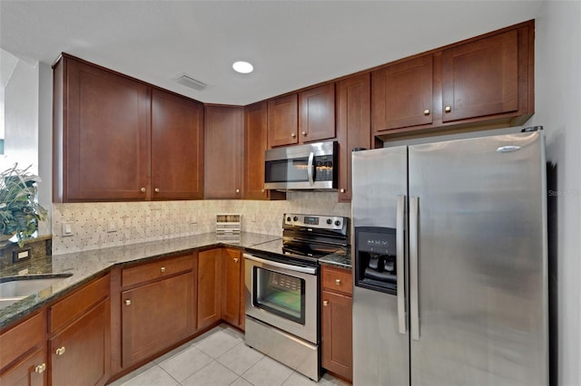 kitchen featuring dark stone countertops, appliances with stainless steel finishes, sink, backsplash, and light tile patterned floors