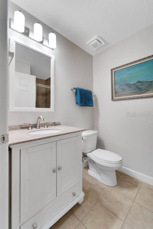 bathroom featuring vanity, toilet, a shower with shower door, and tile patterned floors