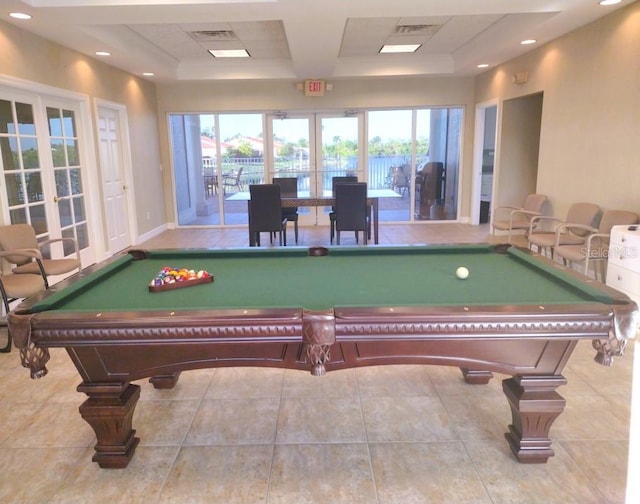 rec room with a tray ceiling, french doors, a wealth of natural light, and light tile patterned floors