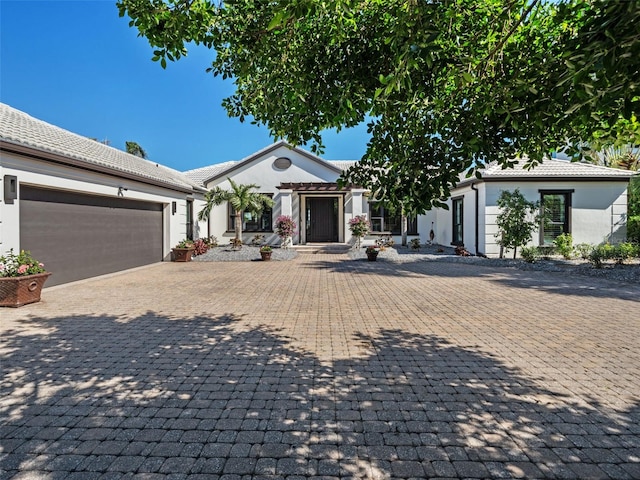 view of front of property with decorative driveway, a tile roof, an attached garage, and stucco siding