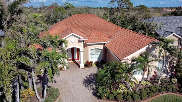 view of front of home with decorative driveway, a tiled roof, and stucco siding