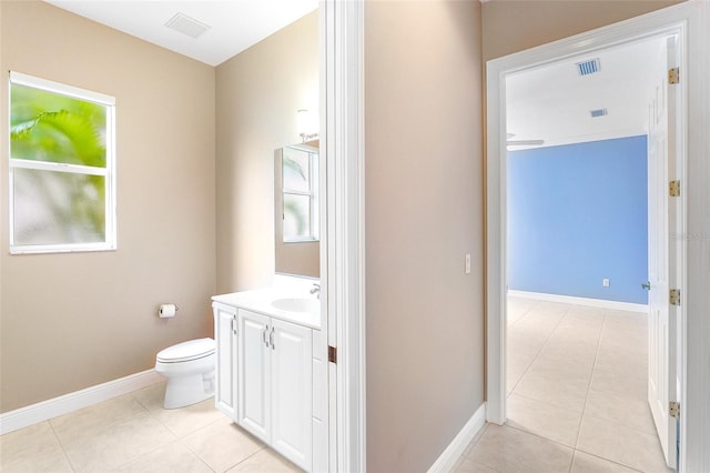 bathroom with toilet, vanity, visible vents, and baseboards