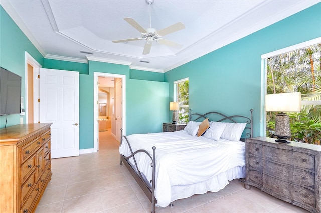 bedroom featuring ornamental molding, a tray ceiling, ensuite bathroom, and light tile patterned floors