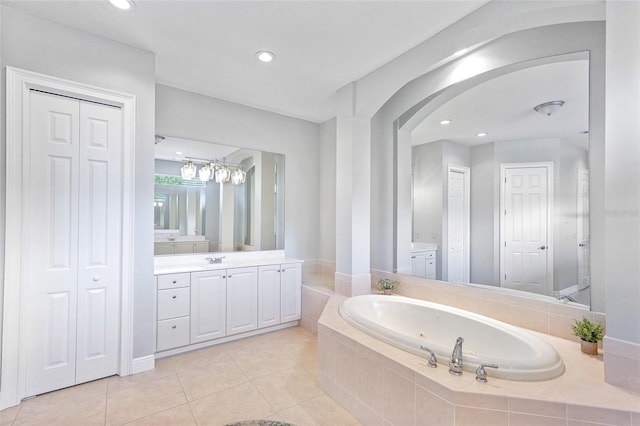 bathroom with a garden tub, vanity, a closet, and tile patterned floors