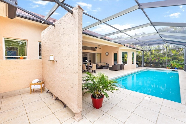 pool with an outdoor hangout area, a patio, ceiling fan, and glass enclosure