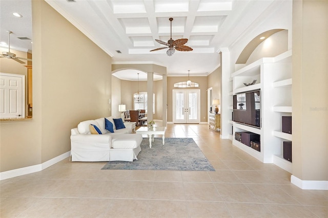 living area featuring built in features, french doors, a towering ceiling, light tile patterned flooring, and ceiling fan with notable chandelier