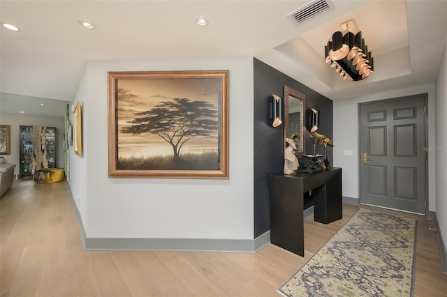 entryway featuring a tray ceiling and light hardwood / wood-style floors