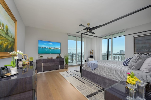 bedroom featuring ceiling fan, wood-type flooring, access to exterior, and floor to ceiling windows