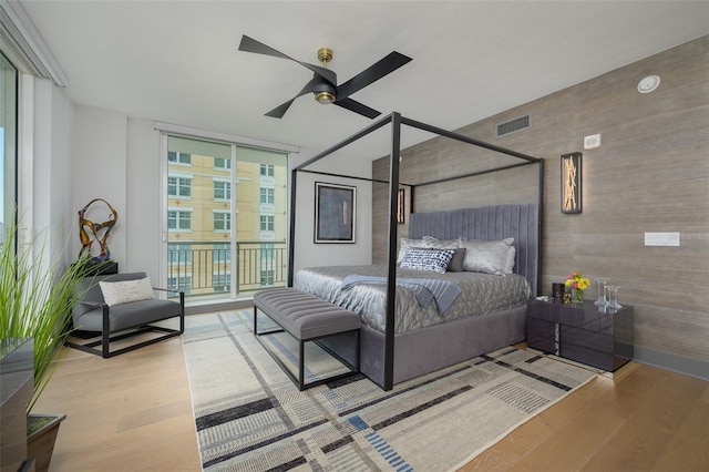 bedroom featuring light hardwood / wood-style flooring, a wall of windows, ceiling fan, and access to outside