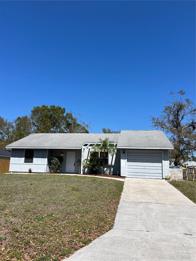 view of front of property with an attached garage, driveway, fence, and a front lawn