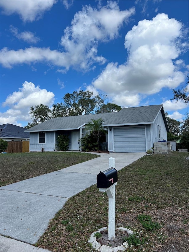 ranch-style home featuring a front yard, driveway, an attached garage, and fence