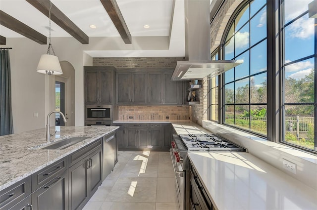 kitchen featuring dark brown cabinetry, decorative backsplash, appliances with stainless steel finishes, decorative light fixtures, and a sink