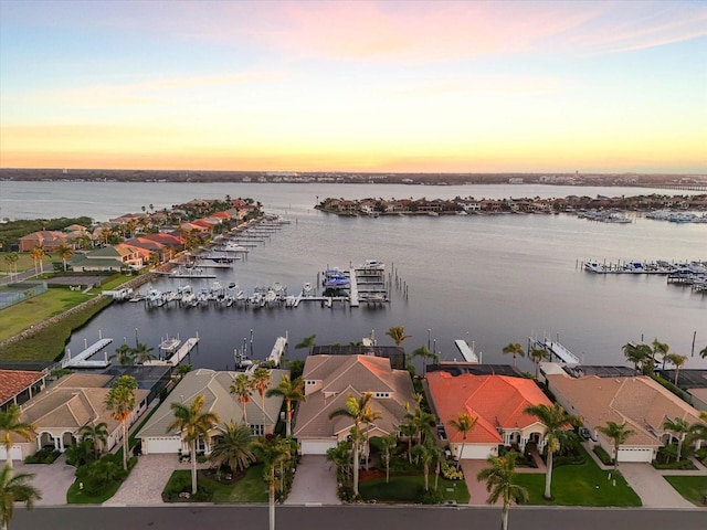 aerial view at dusk with a water view and a residential view