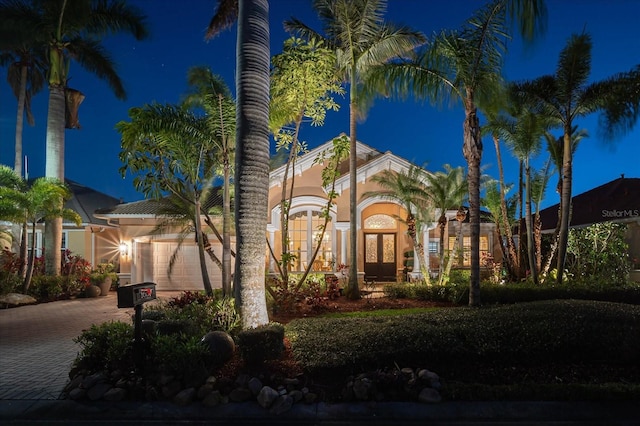 mediterranean / spanish home with french doors, decorative driveway, an attached garage, and stucco siding